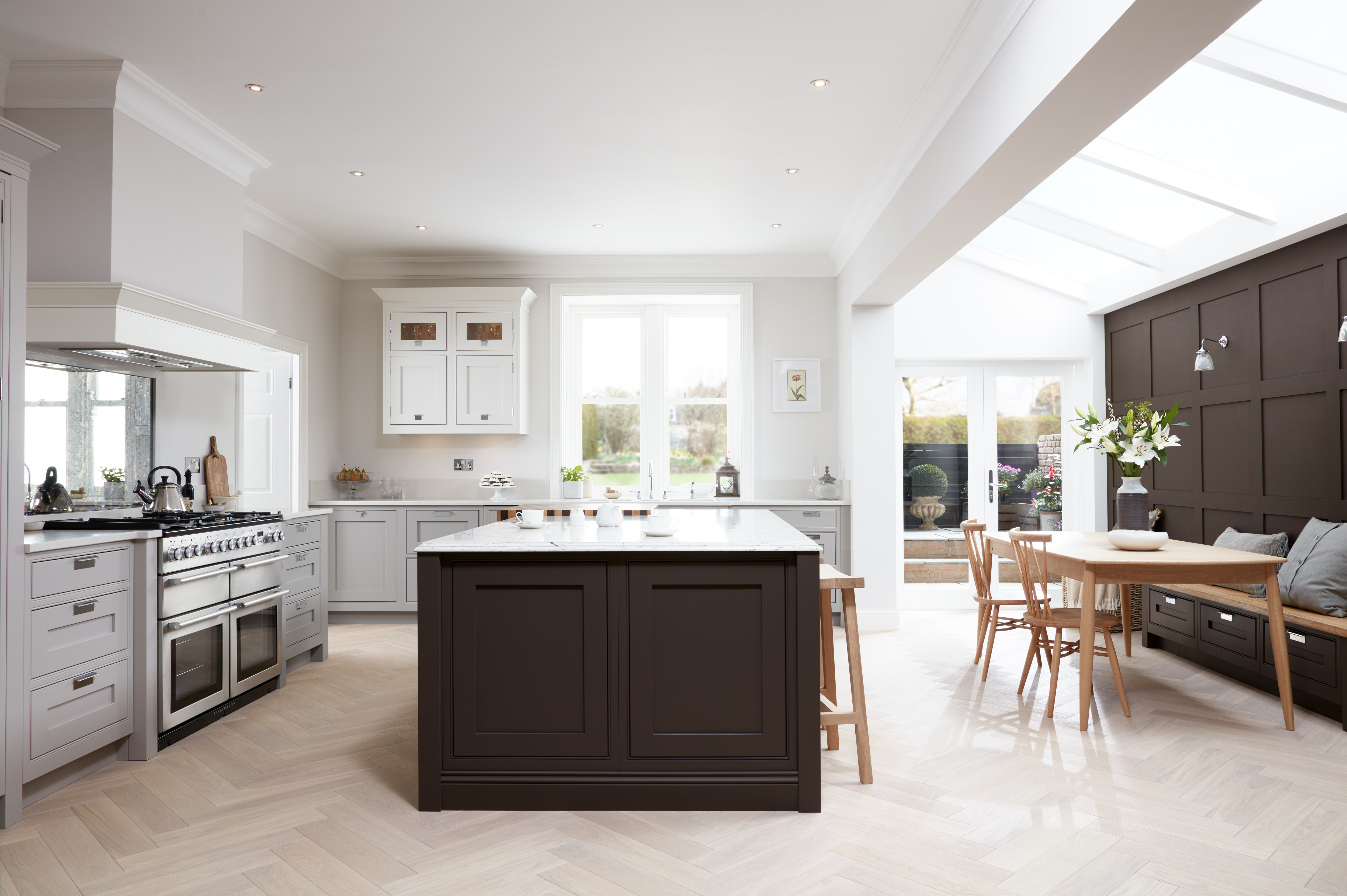 A bright an spacious Ovolo kitchen with a kitchen island, range cooker, dining area and skylight.